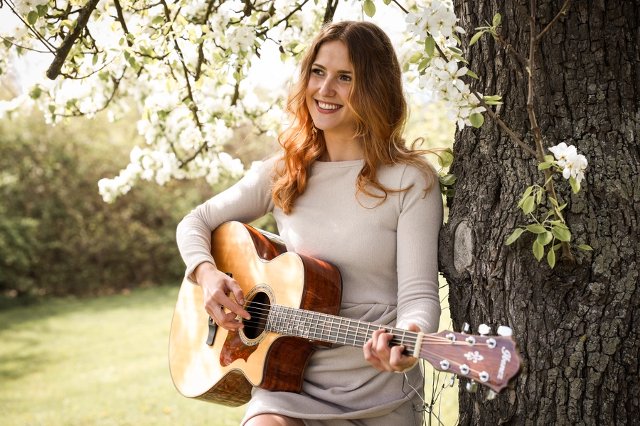Diana lachend und sitzend mit ihrer Gitarre